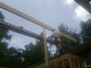 Carpenter setting a ridge beam over a new addition frame — Ice Dam Removal by Roofing Brothers in Brogan