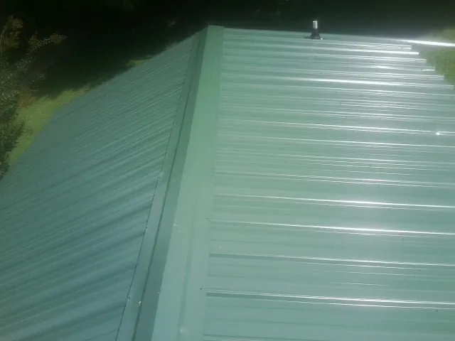 New green metal panels meeting at the ridge of a roof — Flat Roof Repair work by our crew in Brogan