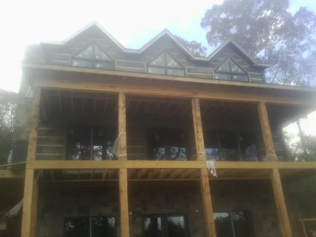 Dormers and porch framing on a large log home under construction — Roof Coating work by our crew in Brogan