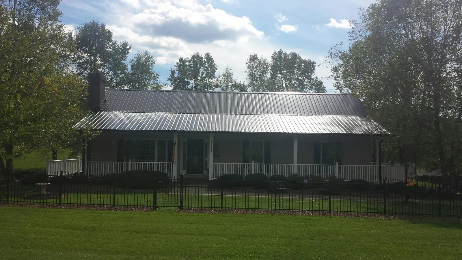 Gray metal roof on a brick ranch with a full width front porch — Gutter Guard Installation work by our crew in Brogan