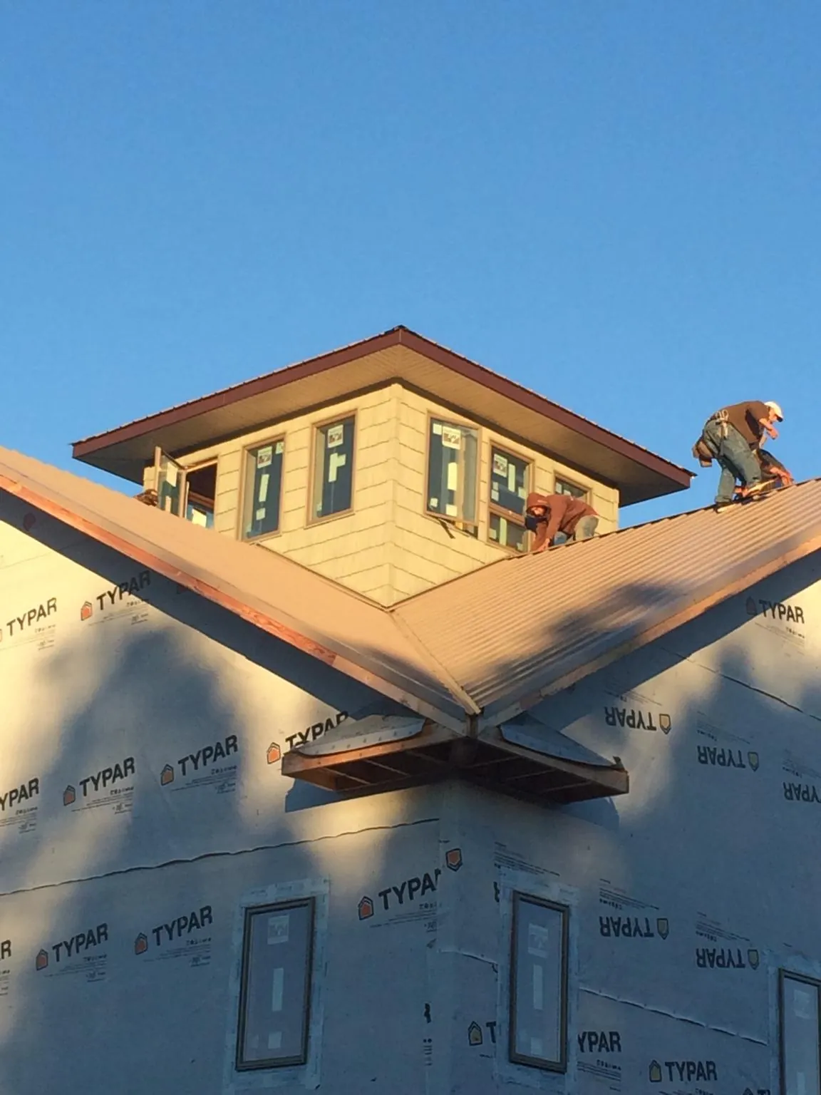 Roofers working around a rooftop cupola on a new metal roof at sunset — Roof Waterproofing in Brogan by Roofing Brothers